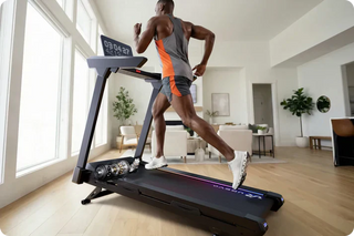 Man running on an incline treadmill in a bright home gym