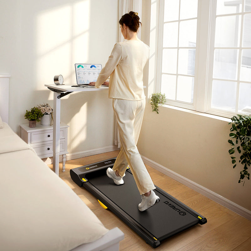 Woman works at standing desk while walking on the UREVO SpaceWalk Lite Walking Pad