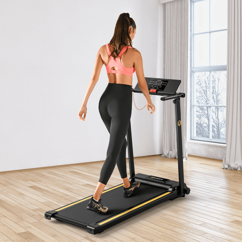 A woman in a pink sports bra and black leggings walks on a treadmill