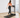 A woman in a pink sports bra and black leggings walks on a treadmill