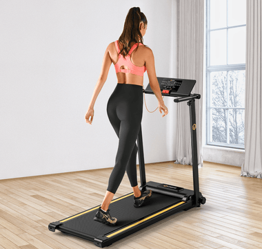A woman in a pink sports bra and black leggings walks on a treadmill