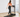 A woman in a pink sports bra and black leggings walks on a treadmill