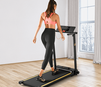 A woman in a pink sports bra and black leggings walks on a treadmill