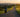Woman walking a long paved trail at sunrise toward a distant city skyline
