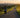 Woman walking a long paved trail at sunrise toward a distant city skyline