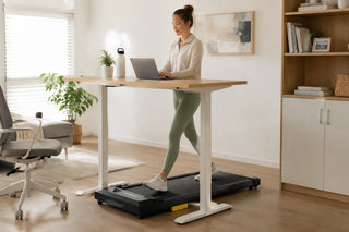 Woman using a walking pad while working at a standing desk in a modern home office
