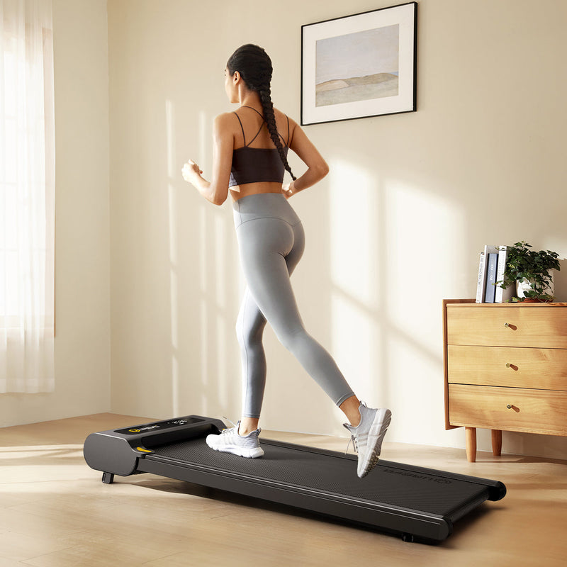 A woman enjoys an indoor run on the UREVO SpaceWalk E1 Walking Pad in her home