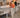 A modern open-plan office with a woman walking beside a desk that has a walking pad treadmill underneath it.