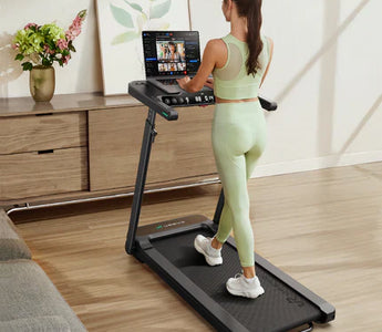 用英语描述这张图片，字符在80以内 Preview  A woman in light green workout attire using a treadmill with a screen displaying multiple video options.