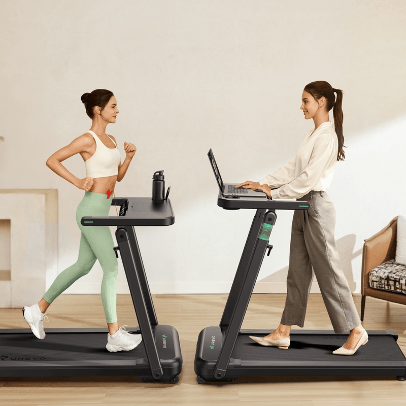Two women use treadmills: one exercises in sportswear, while the other works on a laptop in casual attire.