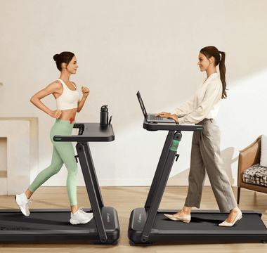 Two women use treadmills: one exercises in sportswear, while the other works on a laptop in casual attire.