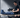 A man in a gym smiles while using a blue leg compression device on his right leg.