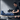 A man in a gym smiles while using a blue leg compression device on his right leg.