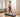 A woman walking on a treadmill in a bright, spacious living room with large windows.