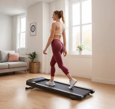 A woman walking on a treadmill in a bright, spacious living room with large windows.