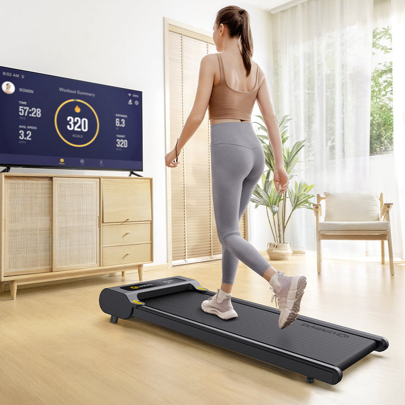 Woman uses Urevo Spacewalk E3 Treadmill, views workout data on TV.