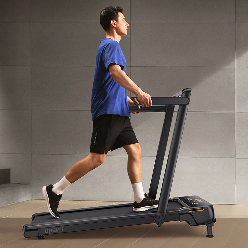  A man in a blue shirt and black shorts is walking on a treadmill.