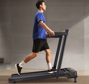  A man in a blue shirt and black shorts is walking on a treadmill.