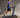  A man in a blue shirt and black shorts is walking on a treadmill.