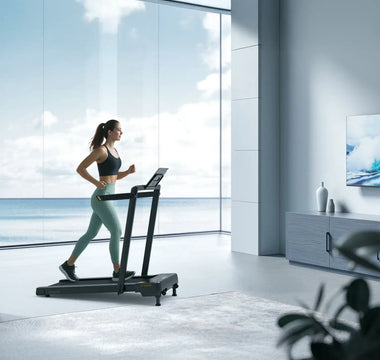 A woman runs on a treadmill in a modern living room with large windows overlooking the ocean, enjoying a scenic workout.