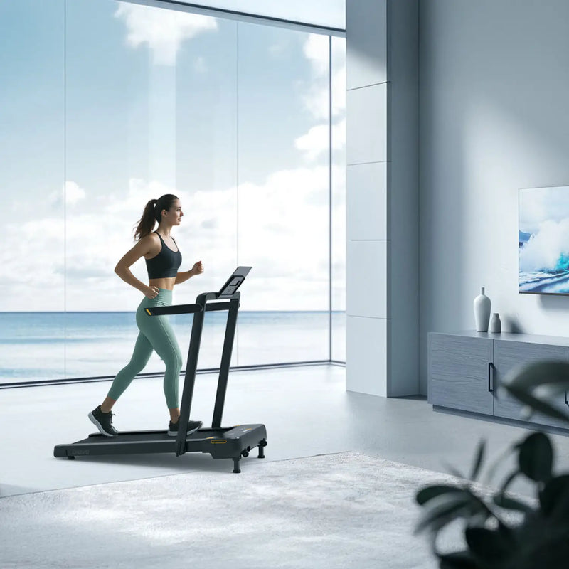 A woman runs on a treadmill in a modern living room with large windows overlooking the ocean, enjoying a scenic workout.