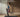 A woman in blue and pink athletic wear is running on a treadmill in a room with curtains.