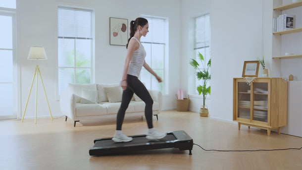 UREVO Spacewalk 2 Treadmill in a modern living room, with a woman walking on it.